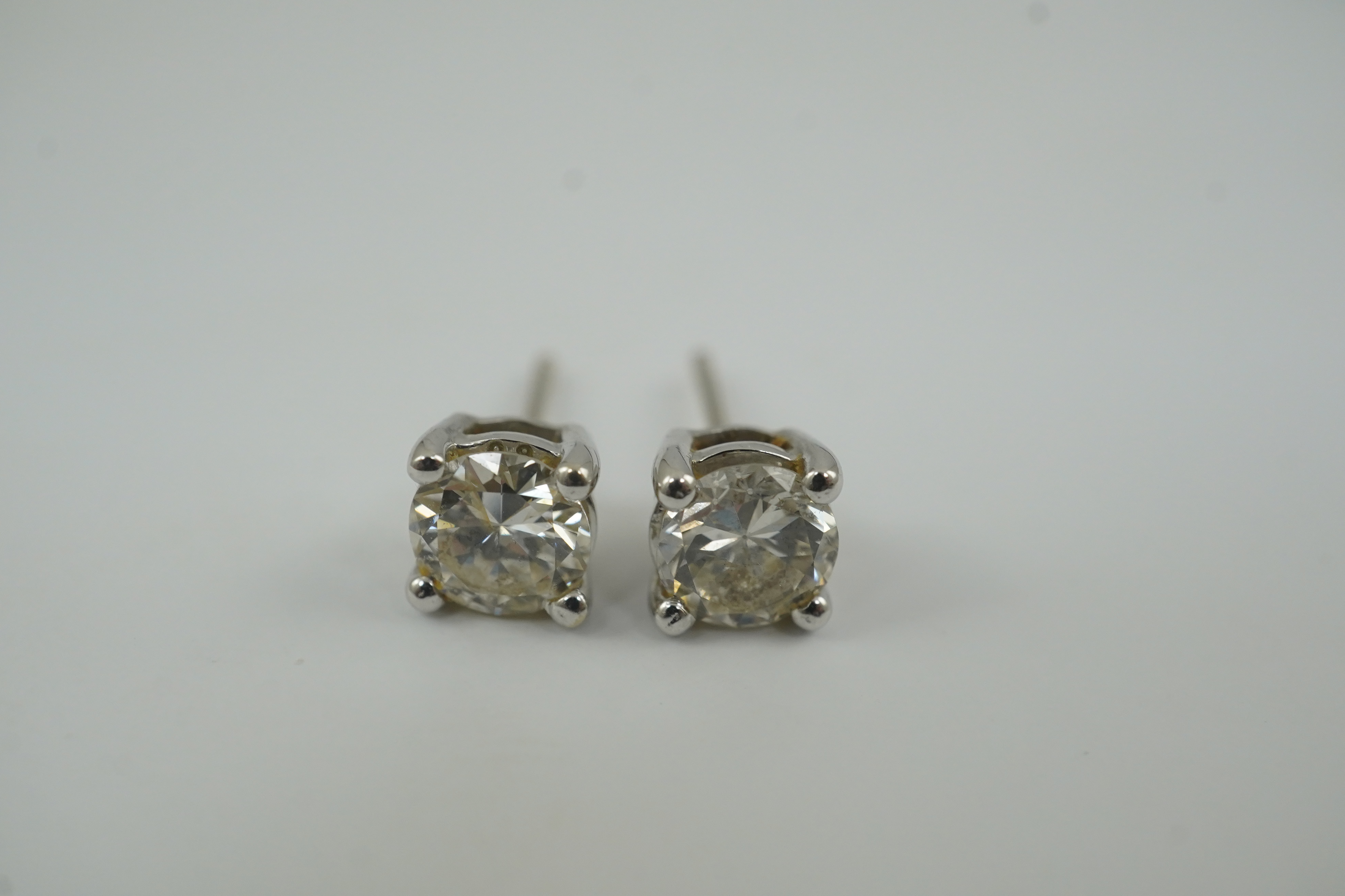 A modern pair of 18k white gold and solitaire diamond set ear studs